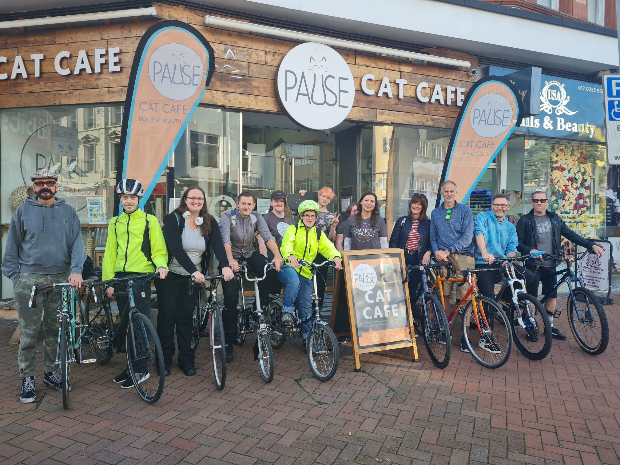 A row of people on their bicycles in front of a cafe.